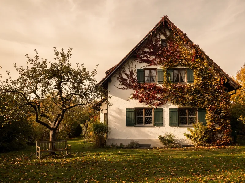 Älteres Familienhaus mit grünen Läden im Herbstlicht